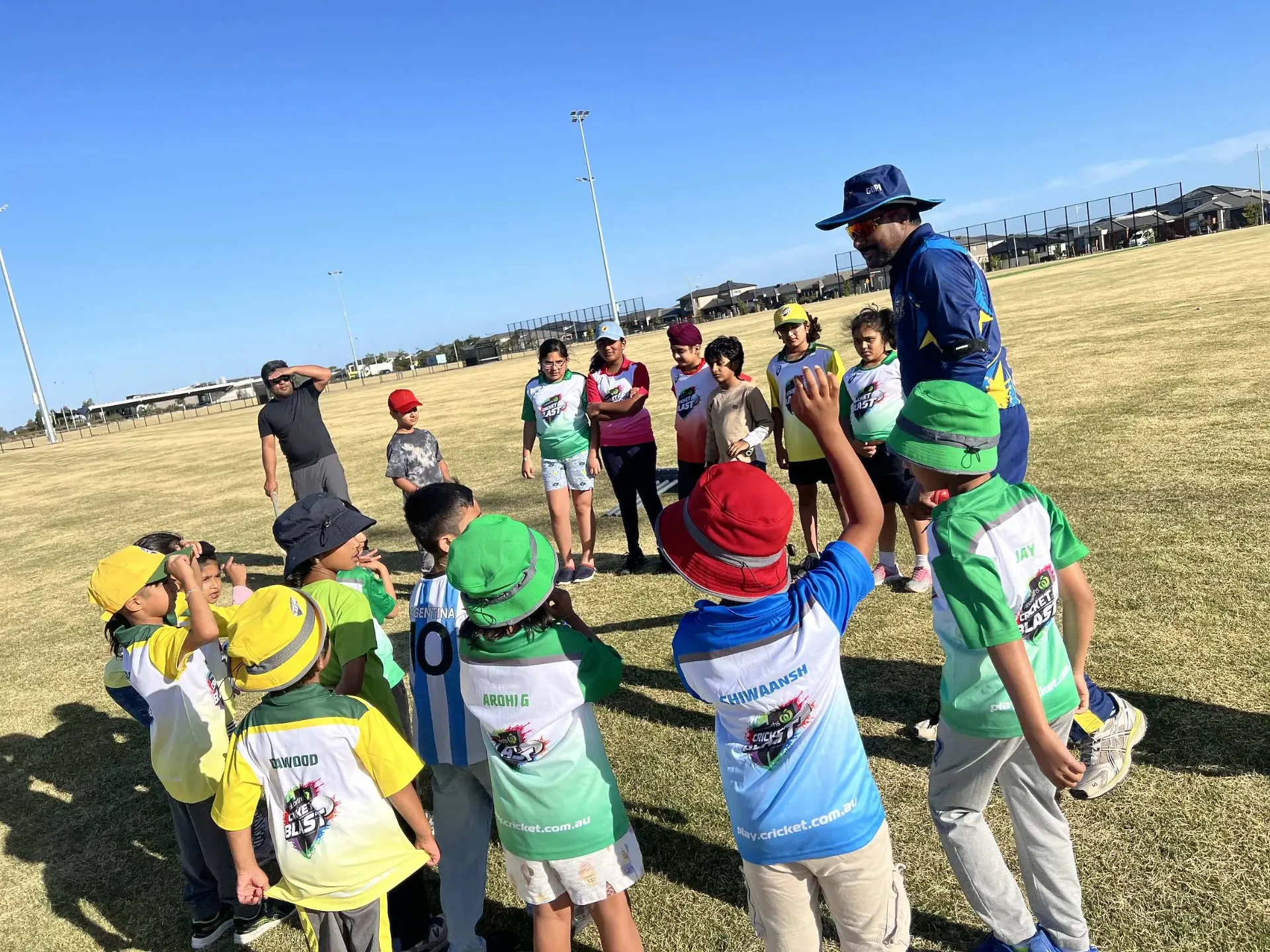 Cricket Blast players gathered around their coach on the ground